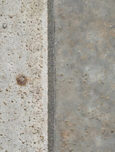 Close-up of a perfectly sealed pool expansion joint with professional gray mastic and sand texture.